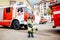 Child, cute boy, dressed in fire fighers cloths in a fire station with fire truck, childs dreamed profession