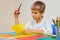 Child cutting colored paper with scissors at the table