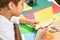 Child cutting colored paper with scissors at the table