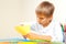 Child cutting colored paper with scissors at the table