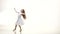 Child dances in a beautiful white dress on a parquet floor. White background. Slow monion