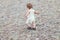 Child dancing outdoors. Little baby girl walking away. Running away little baby girl in steppe. Big landscape environment