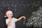 Child decorates a Christmas tree drawing on blackboard.