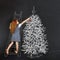 Child decorates a Christmas tree drawing on blackboard. Christmas holiday concept.