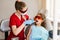 Child dentistry. Uv illumination of photopolymer tooth filling procedure. Child dentist in red protective glasses treats