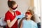 Child dentistry. Uv illumination of photopolymer tooth filling procedure. Child dentist in red protective glasses treats