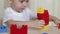 Child development: the boy is playing with colored blocks on the table. The boy collects hands the designer