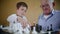 Child development, cheerful grandfather with glasses for sight and happy grandson are smiling and playing chess