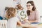 A child with development problems with a professional speech therapist during a meeting. Tutor holding a prop poster of a snake as