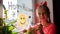 Child in devil horns painting pumpkin on window preparing celebrate Halloween. Little kid draws decorates room interior paper bats