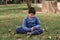 Child with disabilities enjoying outdoors while sitting on a grass in a park.