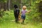 Child and dog,little boy running with black hovie alone forest path