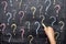 Child drawing colorful question marks on blackboard