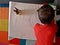 Child drawing a stronghold on a large sheet of paper.