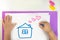 a child draws a house on white paper with crayons, the concept of a family and a cozy home, love and happiness