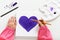 Child draws purple acrylic paint heart with paintbrush on canvas.