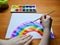 a child draws a rainbow with watercolors on a white sheet of paper. chasing a rainbow is a sign of hope and recovery. close up