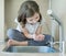 Child drinking water in kitchen at home. Thirsty baby. Hands open for drinking tap water. Pouring fresh drink. Water quality check