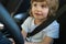 Child driver. Cute child boy while driving car as driver. Baby kid sitting in seat.