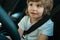 Child driver. Cute child boy while driving car as driver. Baby kid sitting in seat.
