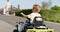 A child driving a toy electric car in a park on a summer day