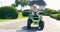 A child driving a toy electric car in a park on a summer day