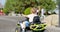 A child driving a toy electric car in a park on a summer day