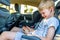 Child with earphones inside car watching movie or listening music on his smartphone