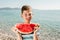 Child eating juicy watermelon. Kids emotions boy eating watermelon on the background of the sea, the beach, the sea coast