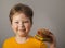 Child eats burger on grey background. Male child with hamburger