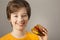 Child eats burger on grey background. Male child with hamburger