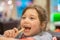 The child eats french fries cheerfully. A little girl opens her mouth to eat a slice of potatoes. Portrait of a child in a fast