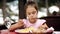 Child eats spaghetti pasta in the restaurant which is located on the shore