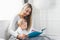 Child education. Happy mother with her toddler sitting on the bed and reading a book