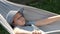 Child, elementary school age girl lying in a hammock outdoors, resting, bored kid lying down outside, funny shot, side view, one
