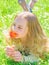 Child enjoy aroma of tulip while lying at meadow, close up. Tenderness concept. Girl on happy face holds red tulip