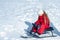 Child enjoying the ski slopes. Little girl enjoy a sleigh ride. Toddler kid girl riding a sledge. Children play outdoors