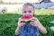 The child enjoys eating delicious, red, ripe, juicy, appetizing watermelon.