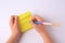 Child erasing word Mistake written with erasable pen on sticky note against white background, top view