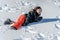 Child falling down in snow. One Asian girl lying on the ground in winter