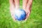 Child and father holding planet Earth in hands against green spring background.