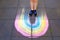 Child feet standing on chalk drawin rainbow.