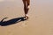 Child feet walk on wet sea sand, back view