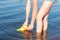 Child fills the water gun in the river, close-up