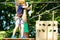 Child in forest adventure park. Kid in orange helmet and blue t shirt climbs on high rope trail. Agility skills and climbing