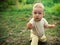 The child found a flower in the grass, plucked the plant and stretched it forward.