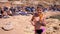 Child with Fresh Juice in his Hands is Standing on a Rocky Coral Beach in Egypt.