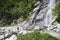 Child in front of a big waterfall through the stone