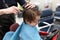 The child is getting a haircut at the hairdresser in a red car. The first haircut of the child in the hairdresser. Toddler child