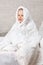 Child girl in blanket sitting on bed